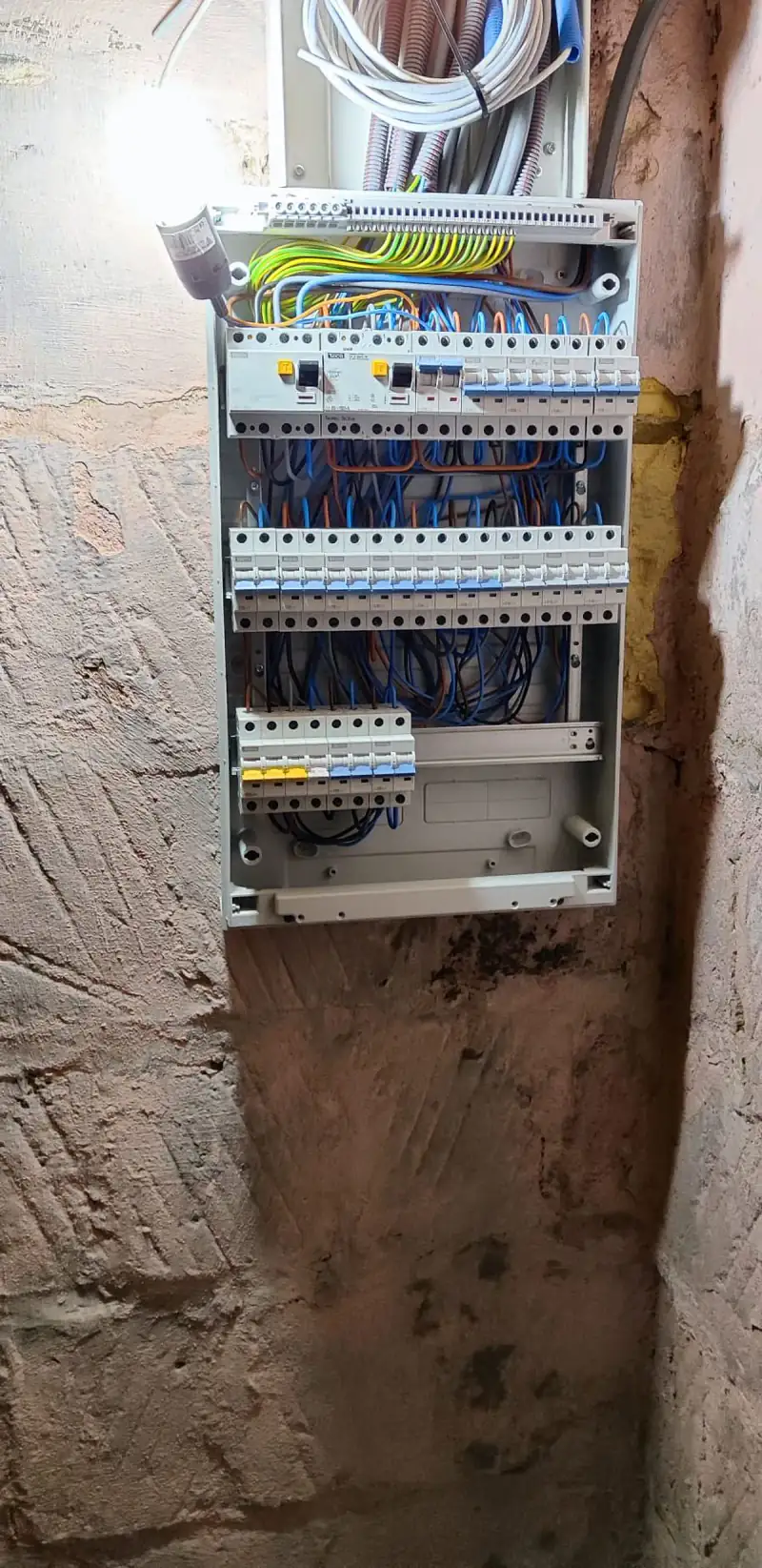 Tableau électrique neuf dans une cave, sous une ampoule