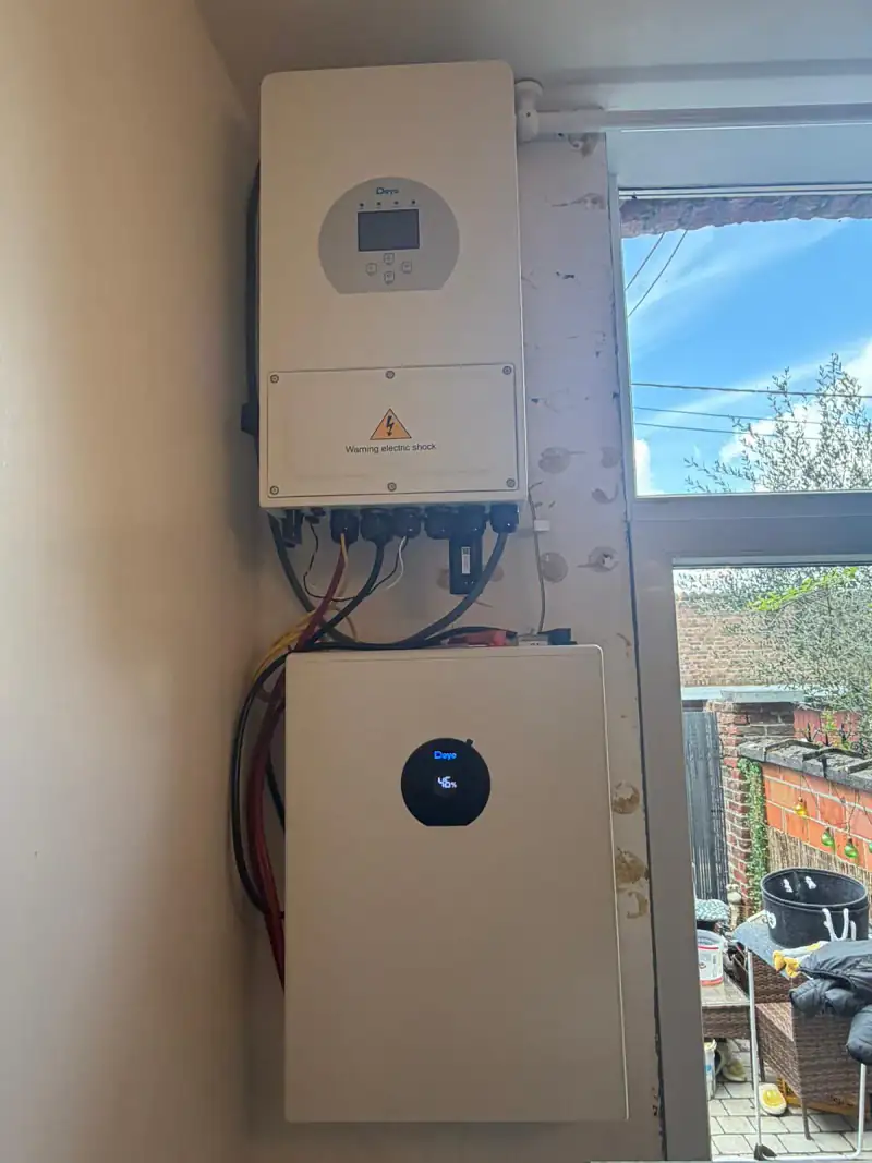 Onduleur et batterie domestique fixés au mur, à côté d'une fenêtre